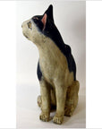 Close-up of a hand-carved black and white cat figurine facing left against a plain background.