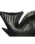 Close-up of dark hand-carved fish sculpture, textured tail and scales visible, on white background.
