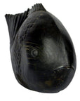 Close-up of dark stone fish sculpture with detailed scales and fins, rounded body, facing slightly right.