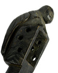 Brown wooden lute with a carved bird on top, rectangular base with holes, shown close-up.