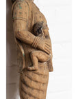Brown hand-carved wood statue of a mother holding child, Indian temple carving from Gujarat, on white background.