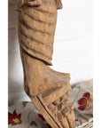 Brown hand-carved wooden statue of Indian mother and child, close-up, on floral fabric background.