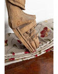 Brown wood mother and child statue on floral fabric, Indian style carving, indoor setting.