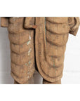 Close-up of brown carved wood statue from Gujarat showing mother and child with ribbed texture.