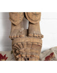 Brown carved stone statue of a mother and child from Gujarat, Indian temple art, indoors.