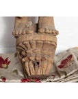 Close-up of brown carved wooden feet on Indian temple statue from Gujarat, mother and child motif.