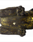 Close-up of gold-brown painted wood carving underside with two rounded feet, worn finish visible.