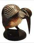 Wooden hand-carved Indonesian kiwi bird with detailed feathers and long beak on sturdy base, close-up.