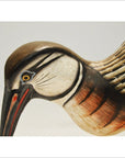 Close-up of brown, white, and black hand-carved wooden Indonesian kiwi bird with rustic detailing.