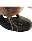 Close-up of painted wooden legs and feet of Indonesian kiwi bird sculpture on dark oval base.