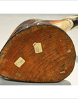 Brown wood hand-carved Indonesian kiwi bird, bottom view showing two old stickers on wooden base.