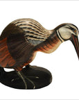 Brown hand-carved wooden kiwi bird with lifelike feathers and long beak on a black base, close-up.