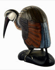 Close-up of a hand-carved wood Indonesian kiwi bird with brown, blue, and orange feathers on a black base.