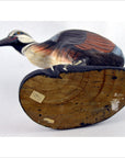 Brown hand carved wood Indonesian kiwi bird figurine lying on its side, visible carved details, flat base, close-up.