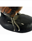 Close-up of brown wood carved kiwi bird legs and feet with detailed feathers and claws on a black base.