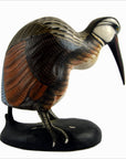 Brown hand carved wood kiwi bird figurine with long beak on black base, displayed indoors.