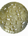 Close-up of green jade medallion with hand-carved robed figures and expressive faces, 2 1/8 inch diameter.