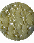 Close-up of green jade medallion with intricate carved patterns and scalloped edges, 2 1/8" diameter.