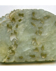 Close-up of green jade medallion with intricate holes and irregular edges, 2 1/4" x 1 3/4" x 1/8".