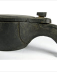 Close-up of rustic metal mortar with handle and sliding top cover, white background.