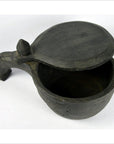 Dark hand-carved wooden mortar with round shape, spout, and sliding top, open on white background.