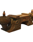 Brown teak wood architectural element with intricate carvings and finials, side view.