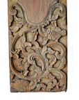 Brown wood hand carved wall plaque with intricate swirling floral and leaf patterns, weathered finish, close-up view.