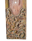 Close-up of weathered wood wall plaques with hand-carved floral and leaf designs in aged tones.