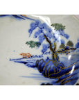 Close-up of blue and gold hand-painted Imari porcelain bowl with landscape design, showing minor imperfections.
