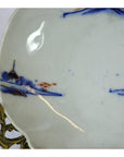 Blue and orange hand painted Imari porcelain bowl on decorative brass stand, close-up view.