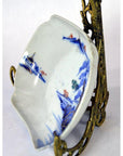 Blue and red hand painted Imari porcelain bowl on ornate brass stand, close-up view.