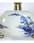 Blue and orange hand painted Imari porcelain bowl on ornate brass stand, close-up.