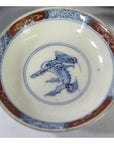 Set of 6 hand painted Imari porcelain small plates with blue mythical center and ornate red and blue rims, close-up.