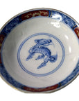 Blue, red, and gold ceramic plate with blue mythical creature pattern, shown on white background.