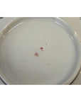 White porcelain bowl with hand painted red Asian characters on base, 7-inch diameter, plain background.