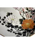 Close-up of a white porcelain Kutani bowl with hand painted orange peonies and green leaves, 7-inch diameter.