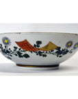 Yellow and red porcelain bowl with white daisy and green leaf pattern, 7 inch diameter, on plain background.