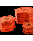 Red-orange hand painted octagonal boxes with metal lid rings, close-up against a black background.