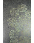 Green ceramic vase with dark speckles and green radial line patterns, abstract flower design, indoors.