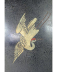 Gold crane with outstretched wings and red crown on dark ceramic vase.