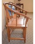 Wooden horseshoe chair with curved backrest and arms on carpet, near a blue and white ceramic vase.