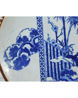 Close-up of white porcelain Igezara plate with floral and bamboo patterns, ridged iron-brown edges.