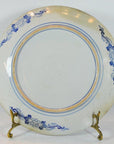 Blue floral Igezara transferware plate with ridged iron brown edges on a decorative metal stand.