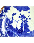 Blue and white ceramic Igezara transferware plate with crane and flower design, brown rim visible on left edge.