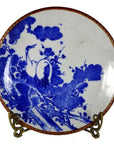 Blue and white ceramic Igezara transferware plate with crane and tree design on a metal stand.