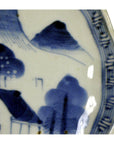 Close-up of a multicolor porcelain Imari Japanese plate with hand-painted landscape, trees, mountains, and geometric border.