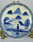 Blue and white porcelain Imari plate with hand painted landscape design, close-up on brass stand.