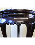 Dark brown lacquer incense stand with scalloped edge and curved legs, low angle view.