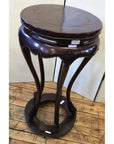 Dark brown lacquered wood incense stand with curved legs on wooden floor, light background, close-up view.