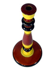 Red, yellow, and black hand-carved wood folk art candlestick, round shape, top view.